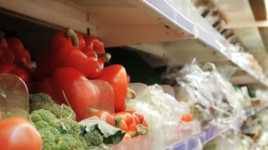 Genç kadın kırmızı biber kırmızı biber stok rafa koymak üzerinde satın alma seçer. taze sebze bakkal market