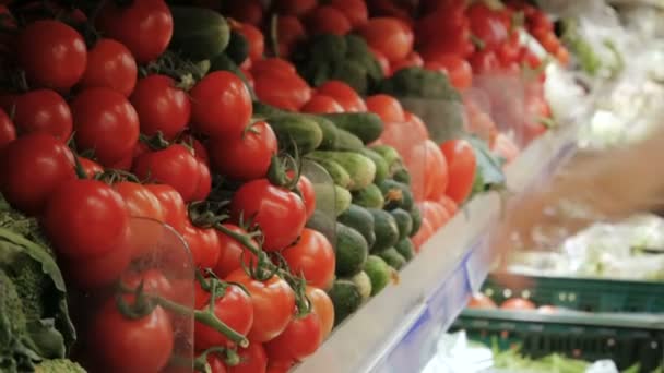 Mujer en un supermercado selecciona los tomates elegir verduras en el supermercado . — Vídeos de Stock