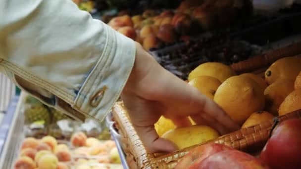 食料品店でレモンを選択する女性手果物やスーパーの野菜売り場でレモンをピックアップします。 — ストック動画