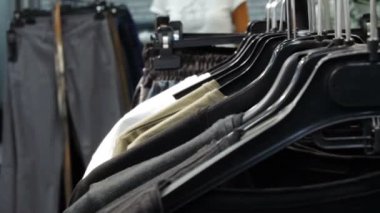 Kadın dükkanda raflar üzerinde asılı olan gömlek bakar. eller bir raf Giysi, bir butik tarama rastlamak. Raf odaklanılan kafa görünümü.