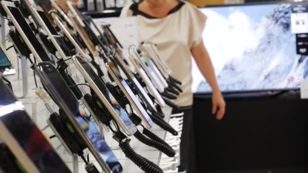 El cliente elige el teléfono inteligente en la tienda de electrónica. Sala de exposición Gadget en la tienda de electrónica, compradores de pruebas de teléfonos inteligentes — Vídeos de Stock