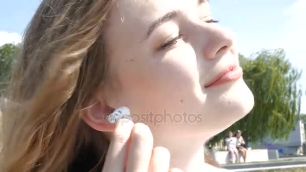 Mujer joven poniendo auriculares auricular en el oído — Vídeo de stock