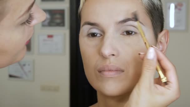 Make-up Specialist kunstenaar maakt een blonde vrouw model mooie zachte make-up vóór een belangrijke gebeurtenis. stap voor stap — Stockvideo