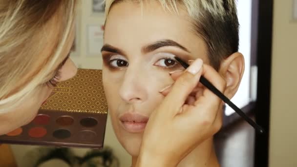 Makeup Specialist artist gör en blond kvinna modell vacker mild makeup eye innan en viktig händelse. steg för steg — Stockvideo