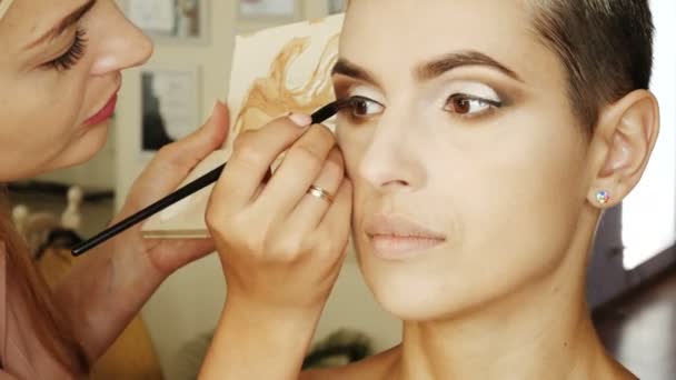 Ειδικό μακιγιάζ καλλιτέχνης κάνει μια ξανθιά γυναίκα μοντέλο όμορφο απαλό μακιγιάζ ματιών πριν από ένα σημαντικό γεγονός. βήμα-βήμα — Αρχείο Βίντεο