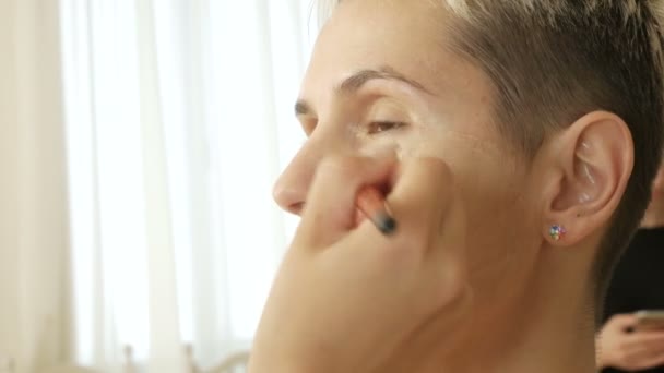 Makeup Specialist artist makes a blonde woman model beautiful Gentle makeup before an important event. step by step — Stock Video