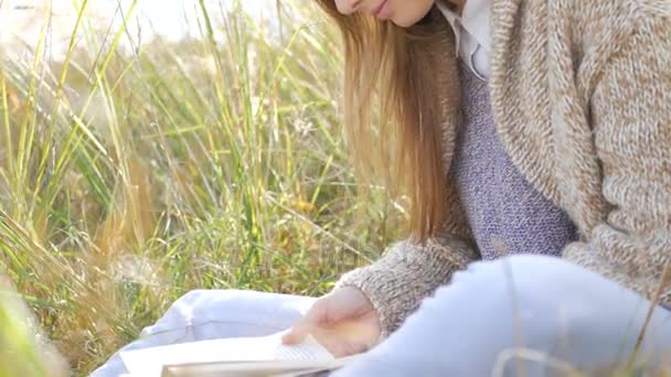 Mujer joven leyendo libro en el parque — Vídeos de Stock