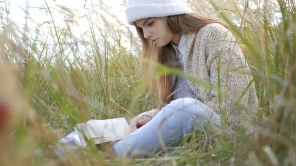 Young woman reading book in park — Stock Video