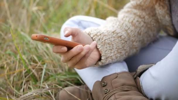 Elegante schöne Frau, die im Park auf dem Smartphone SMS schreibt — Stockvideo