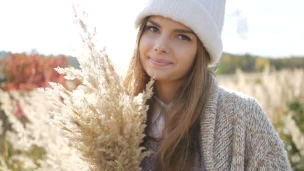 Boldog asszony ősszel, mosolyogva. Örömteli és izgatott fiatal nő birtoklás móka a napsütéses őszi parkban — Stock videók