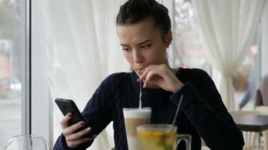 Cafe, kahve Kupası, tatlı Kahvaltı, gülen surat, açık hipster portre, kız moda, Masa, tatlı lezzetli sütlü kahve, aramak için telefon smartphone kullanan genç güzel kadın