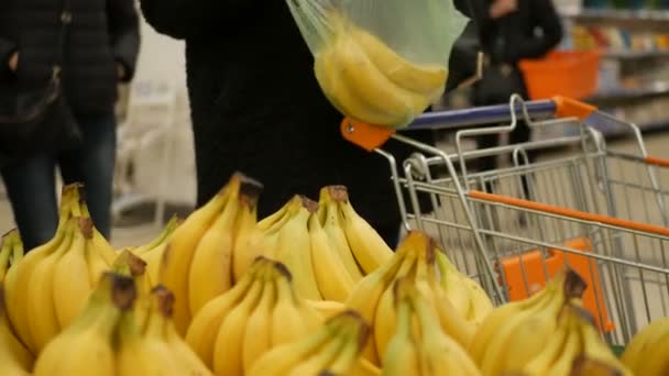 Mujer tomando un plátano en una tienda de comestibles con frutas y verduras — Vídeos de Stock