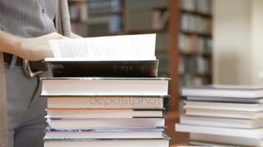 Kadın kitap masada yığını bakar