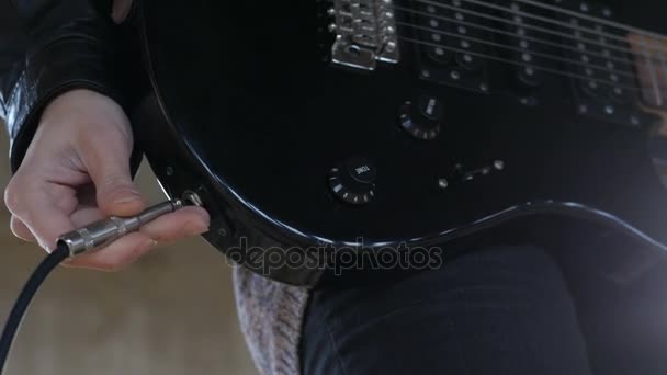 Közelről gitárosának kéz dugulás audio kábel, az elektromos gitár és a kötet és hangszín potméter Tuning