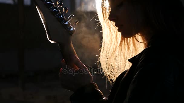 Kvinna gitarrist siluett i en bakgrundsbelysning i röken spelar solo och sjunga — Stockvideo