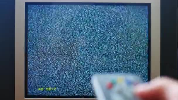 Foto ravvicinata di una mano maschile che tiene il telecomando della TV e cambia canale televisivo senza rumore di segnale — Video Stock