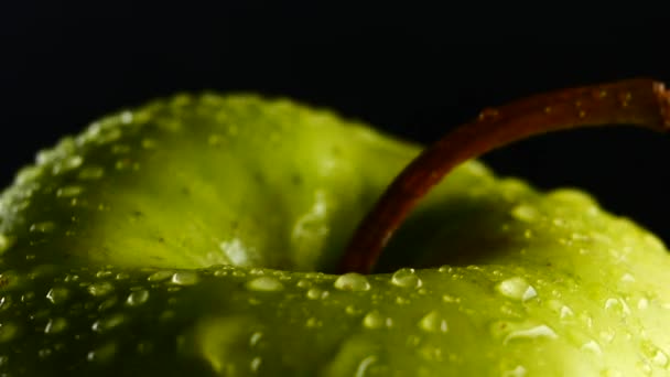 Зеленое яблоко с капельками воды вращается на черном фоне — стоковое видео