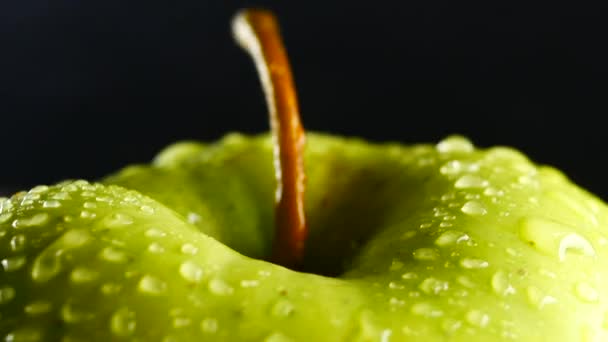 Pomme verte avec gouttes d'eau tourne sur fond noir — Video