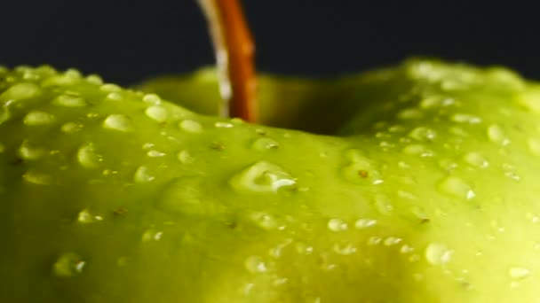 Зелене яблуко з краплями води обертається на чорному тлі — стокове відео