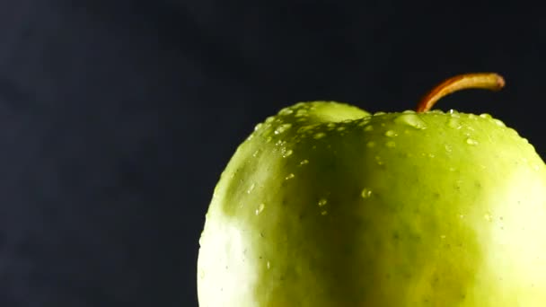 Manzana verde con gotas de agua gira sobre fondo negro — Vídeos de Stock