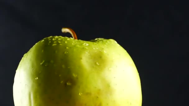 Grüner Apfel mit Wassertropfen rotiert auf schwarzem Hintergrund — Stockvideo