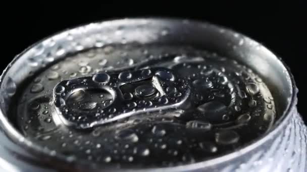 Una bevanda fredda ruota su uno sfondo nero. Gocce d'acqua su lattina di alluminio di soda o birra — Video Stock