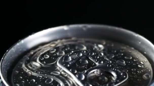 Холодний напій обертається на чорному тлі. Водяні краплі на алюмінієвій банці содової або пива — стокове відео