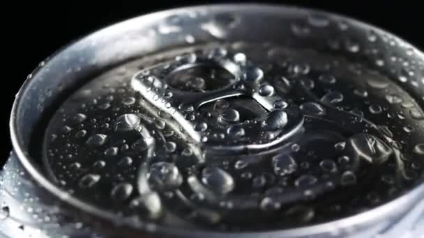 Uma bebida gelada gira contra um fundo preto. Gotas de água em lata de alumínio de refrigerante ou cerveja — Vídeo de Stock