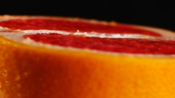 Hälften av grapefrukt, roterande på svart bakgrund — Stockvideo