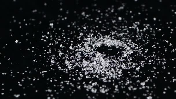 El azúcar dulce o la sal vierten en el montón sobre el fondo negro. Manojo de azúcar de arena blanca derramada — Vídeos de Stock