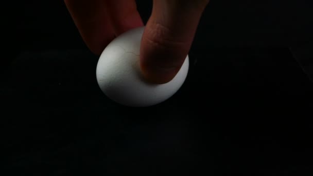 Hand of a man turns a chicken egg on a table — Stock Video