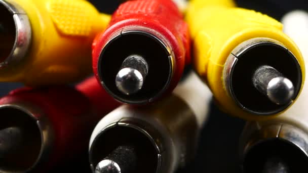 Rode, witte en gele mannelijke cinch stekkers, op zwarte achtergrond — Stockvideo