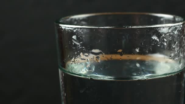 Glas med vatten på en svart bakgrund — Stockvideo