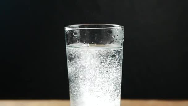 Vidro com comprimido efervescente em água. em preto — Vídeo de Stock