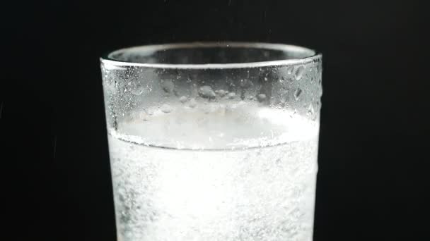 Verre avec comprimé effervescent dans l'eau. sur noir 