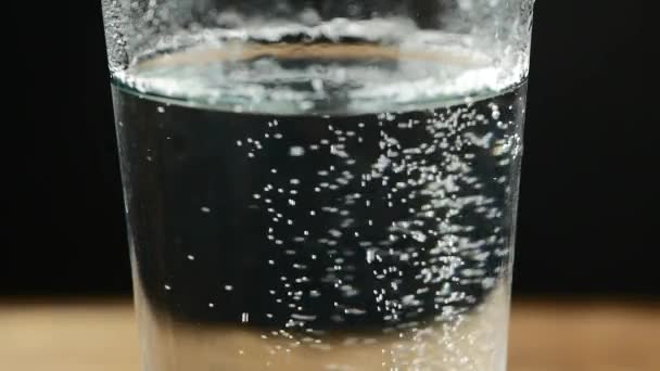 Glas met bruistablet in water. op zwart — Stockvideo