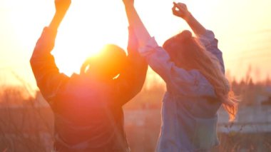 iki genç kadın kolları yukarı kaldırarak günbatımı hayranım. Umut güven, sevgi, tatil ve mutluluk kavramı