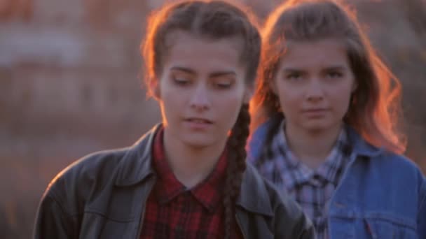Dvě mladé ženy nejlepší přátelé, přejděte do fotoaparátu na pozadí západu slunce. Letní dovolená, dovolená, volný čas, cestování a lidé koncepce — Stock video