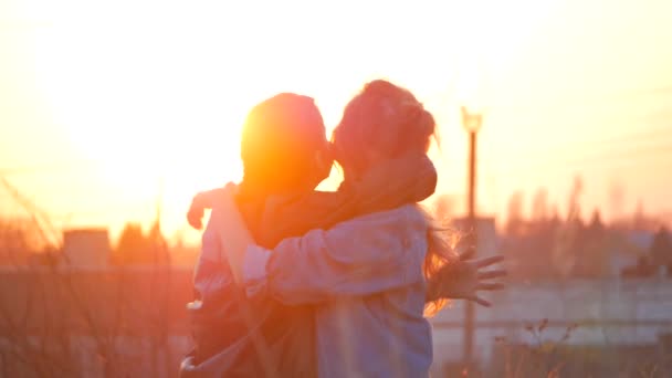 Dos jóvenes felices, hermanas o novias abrazándose en el fondo de la puesta del sol. vacaciones de verano, vacaciones, ocio, viajes y concepto de personas — Vídeo de stock