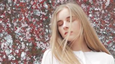 Yaz yaşam tarzı moda bir çiçekli ağaç arka planı beyaz gömlek giymiş genç güzel sarışın şık hipster kadın portresi