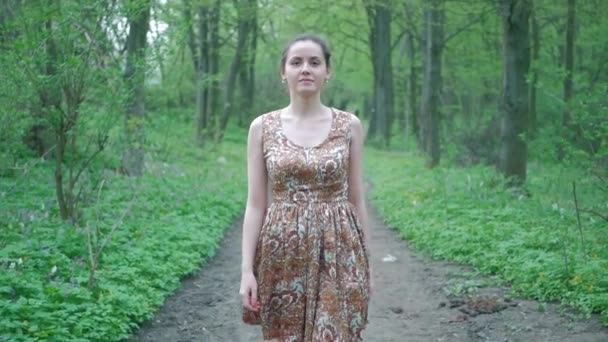 Молодая красивая женщина гуляет по лесу среди деревьев. Иди по тропинке, свежий воздух — стоковое видео