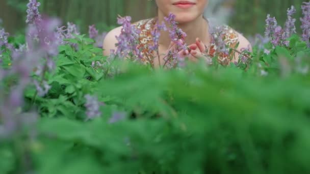 Νεαρή όμορφη γυναίκα απολαμβάνει λουλούδια του δάσους — Αρχείο Βίντεο