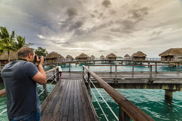 Un homme prend des photos au coucher du soleil dans un bungalow de luxe à Bora Bora — Photo