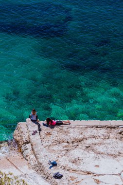İki kız rahatlatıcı bir Costa Brava pier turkuaz denizde 