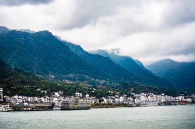 Dağlar ve bulut ile Yangtze nehir kenarında küçük bir kasaba 