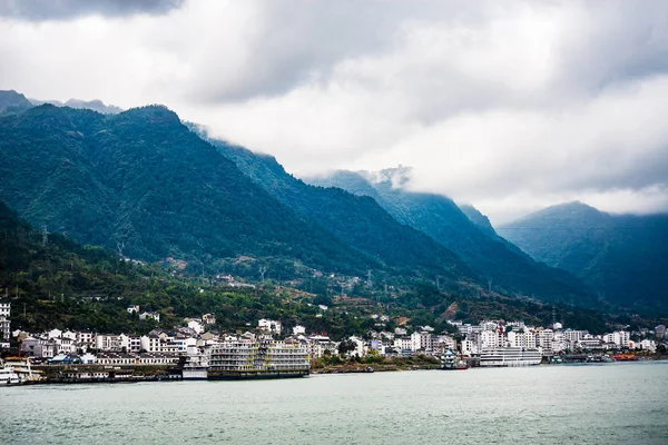 Dağlar ve bulut ile Yangtze nehir kenarında küçük bir kasaba 