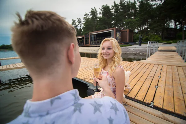 Adam şampanya bir iskele üzerinde oturan bir kadın ile bir tarihte açar