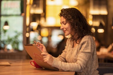 bir fincan sıcak kahve ile bir kafede kız çizer