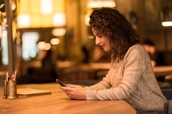 Schattig meisje zitten in Cafe en kijken naar telefoon — Stockfoto