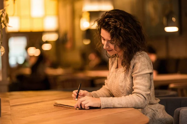 Schattig meisje trekt zitten in een cafe — Stockfoto